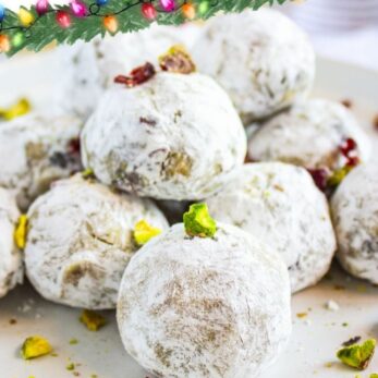 A stack of eggnog pistachio cranberry truffles dusted with powdered sugar sits on white plates, garnished with chopped pistachios and cranberries. Text reads: Eggnog Pistachio Cranberry Truffles. Yummy & Rich.