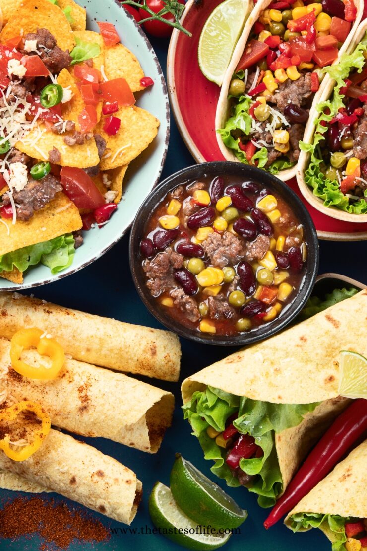 A colorful assortment of Mexican food, including tacos with lettuce and corn, nachos with beef and tomato, rolled tortillas, and a bowl of chili with beans and vegetables, garnished with lime, peppers, and greens.
