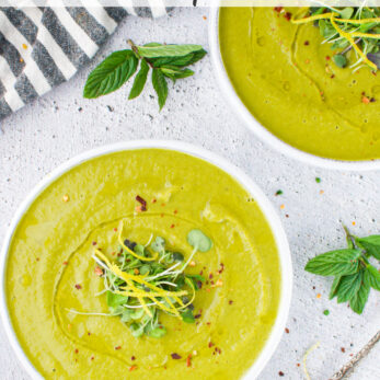 Two bowls of creamy green fennel, lemon, and pea soup garnished with microgreens and chili flakes, placed on a light surface with fresh herbs, a striped napkin, and a spoon nearby. Recipe text is visible at the top.