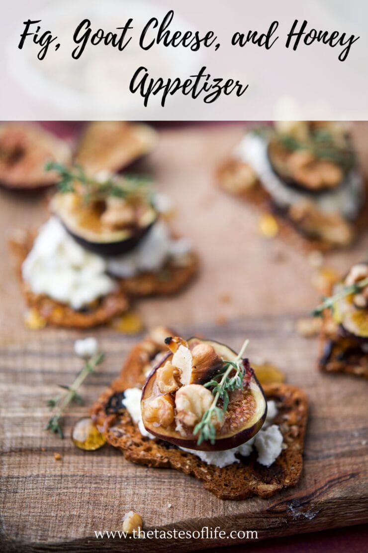 Close-up of a fig, goat cheese, and honey appetizer on a crisp cracker, garnished with walnuts and fresh herbs, placed on a rustic wooden surface. Text at the top reads Fig, Goat Cheese, and Honey Appetizer.
