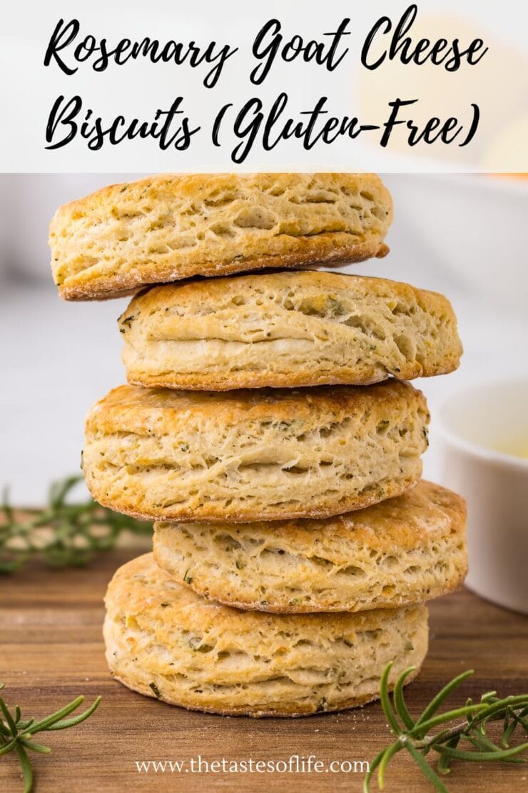 A stack of five golden-brown gluten-free rosemary goat cheese biscuits is shown on a wooden surface, with fresh rosemary sprigs and a bowl blurred in the background. Text reads: Rosemary Goat Cheese Biscuits (Gluten-Free).