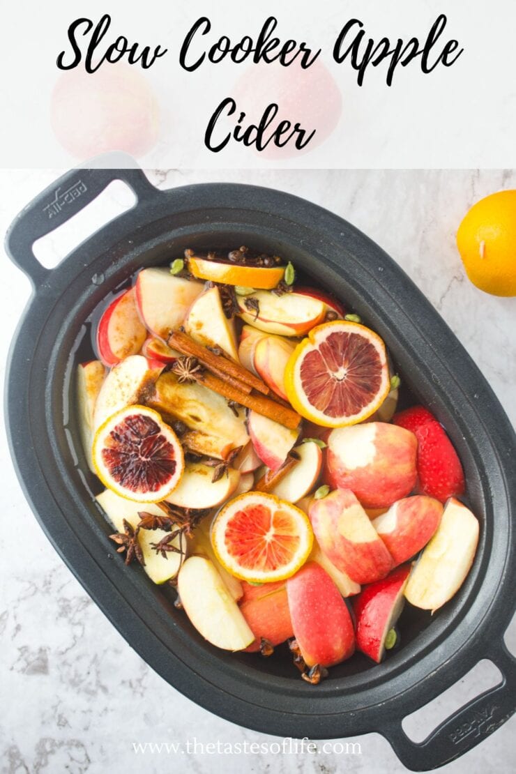 Overhead view of a slow cooker filled with sliced apples, oranges, blood oranges, cinnamon sticks, and star anise, with the text “Slow Cooker Apple Cider” written at the top.