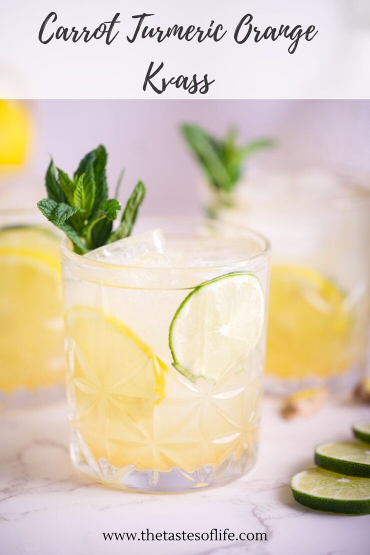 A glass of Carrot Turmeric Orange Kvass with ice, sliced lime, and fresh mint garnish, set on a light surface with more drinks and lime slices in the background. Text reads Carrot Turmeric Orange Kvass.