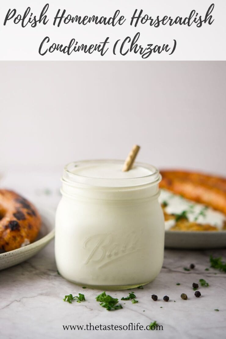 A glass jar filled with creamy horseradish sauce sits on a white surface, surrounded by herbs and peppercorns. Two blurred bread dishes are visible in the background. Text above reads Polish Homemade Horseradish Condiment (Chrzan).