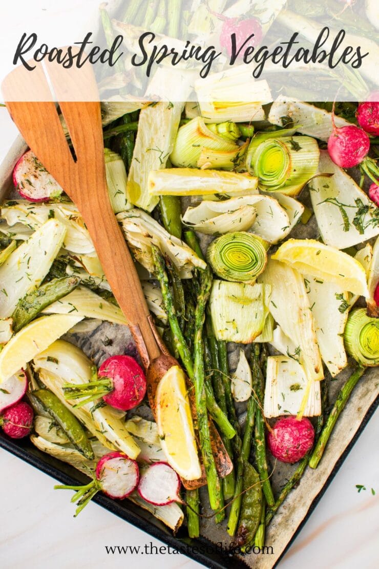 A baking sheet with roasted spring vegetables including asparagus, leeks, radishes, and fennel, garnished with herbs. Wooden tongs rest on top, and “Roasted Spring Vegetables” is written at the top of the image.