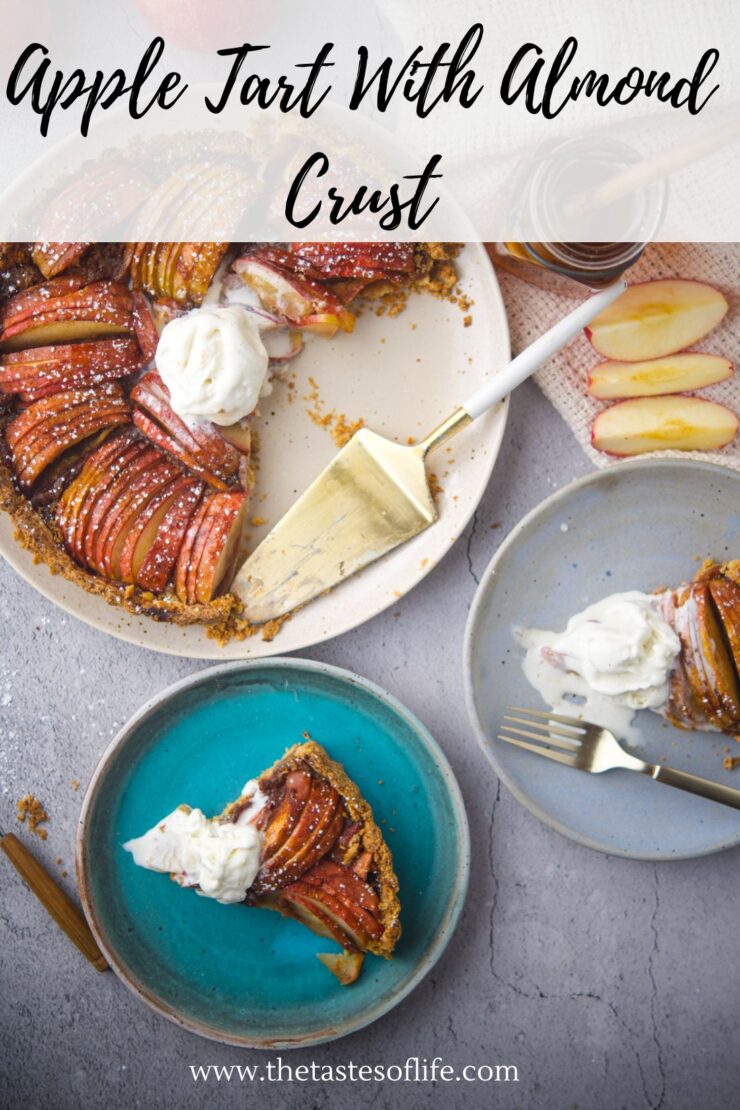 Overhead view of an apple tart with almond crust on a plate, a slice served on a blue dish with whipped cream, a pie server, apple slices, and a fork nearby. Text reads: Apple Tart With Almond Crust.