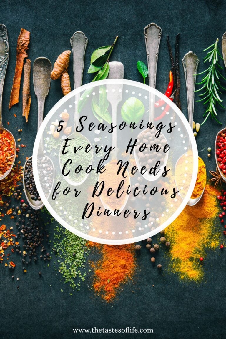 An overhead view of assorted spices and herbs in spoons on a dark surface, with text overlay: 5 Seasonings Every Home Cook Needs for Delicious Dinners. Thetastesoflife.com is written at the bottom.