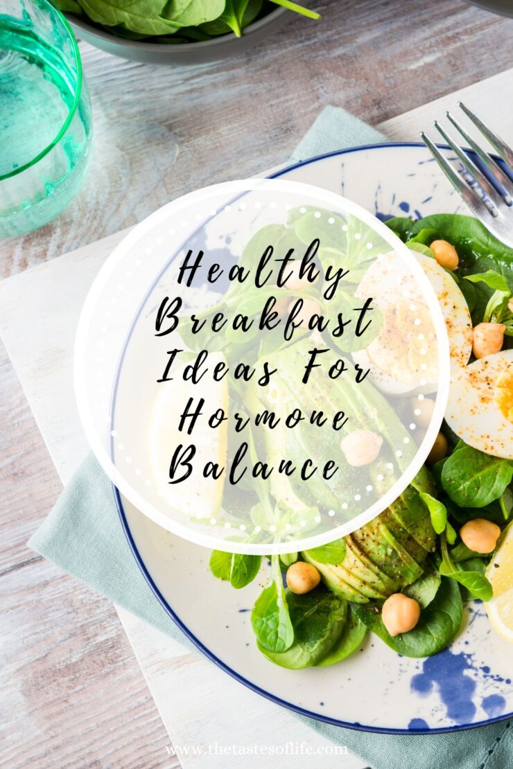 A plate of salad with leafy greens, sliced avocado, chickpeas, and a halved boiled egg sits on a rustic table. Text overlay reads, Healthy Breakfast Ideas For Hormone Balance.