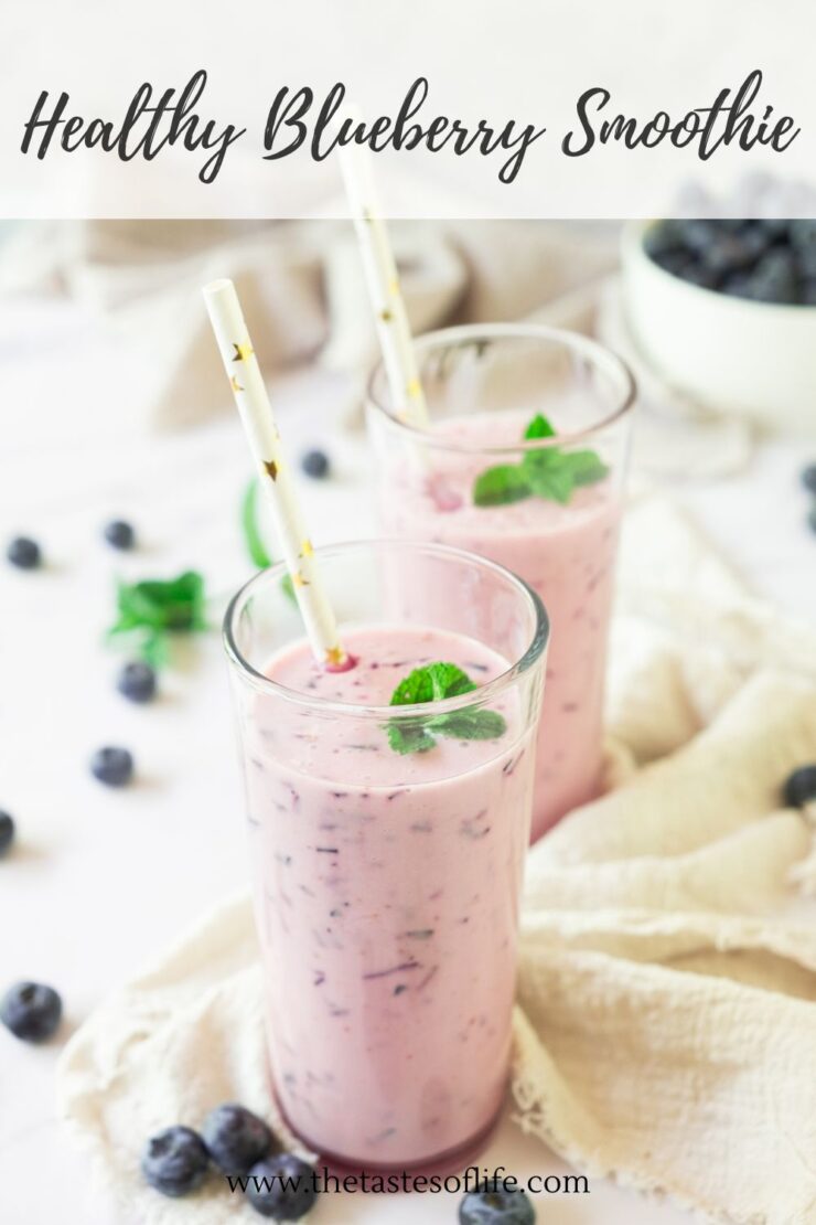 Two tall glasses of blueberry smoothie with mint leaves and paper straws, surrounded by fresh blueberries and a bowl of blueberries in the background. The text reads Healthy Blueberry Smoothie.