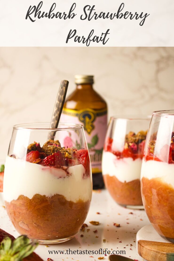 Two glasses of rhubarb strawberry parfait topped with fruit and granola sit on a counter; a spoon is in one glass. A bottle and strawberries are in the background. Text reads Rhubarb Strawberry Parfait and www.thetastesoflife.com.