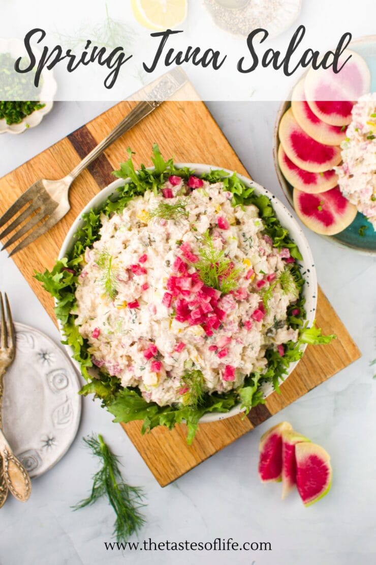 A bowl of tuna salad garnished with lettuce and pink radish, placed on a wooden board, with a fork, dill, and sliced radishes nearby. Text on image reads Spring Tuna Salad and www.thetastesoflife.com.