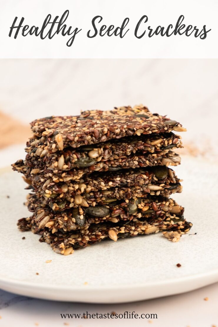A stack of homemade seed crackers sits on a white plate. The crackers are packed with various seeds and grains, appearing crisp and textured. The text above reads Healthy Seed Crackers.