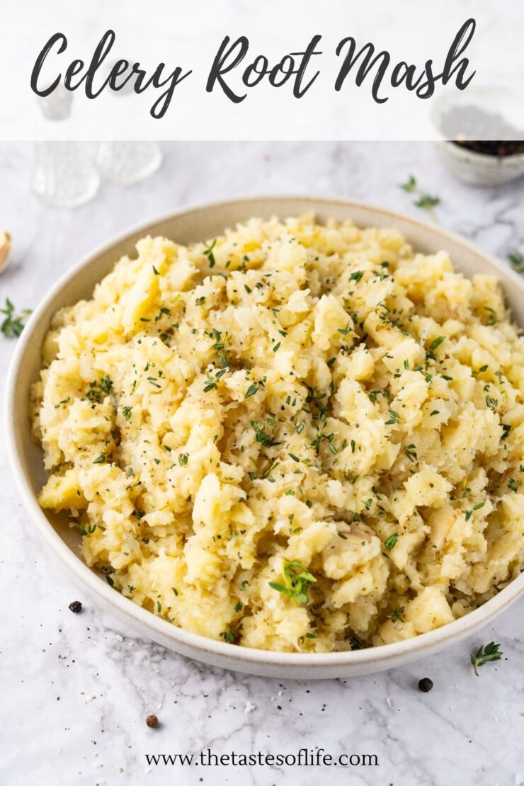 A bowl of creamy celery root mash, garnished with fresh herbs, sits on a light marble surface with scattered peppercorns and thyme.