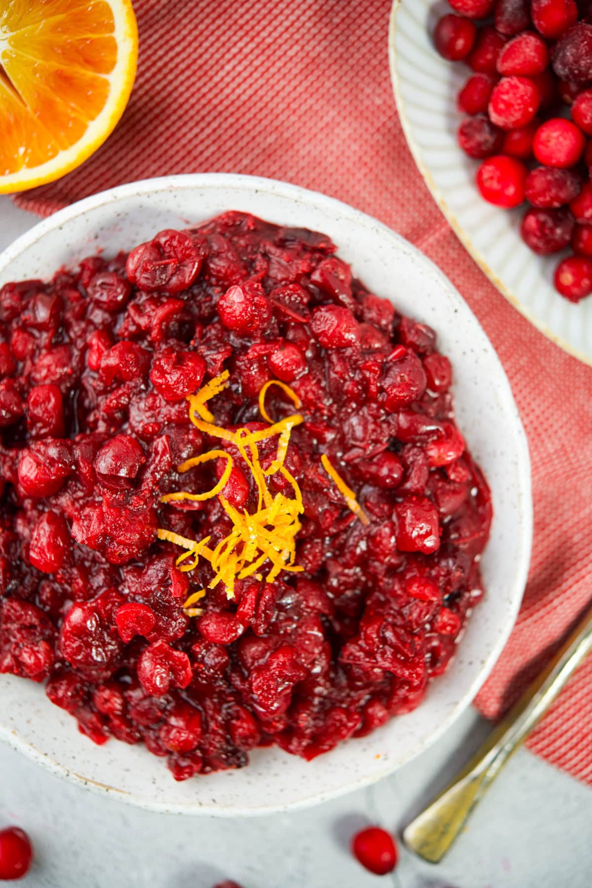 Fresh homemade cranberry sauce garnished with orange zest in a white bowl for holistic cooking.