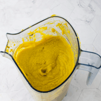 Creamy yellow soup or smoothie in a glass blender pitcher.