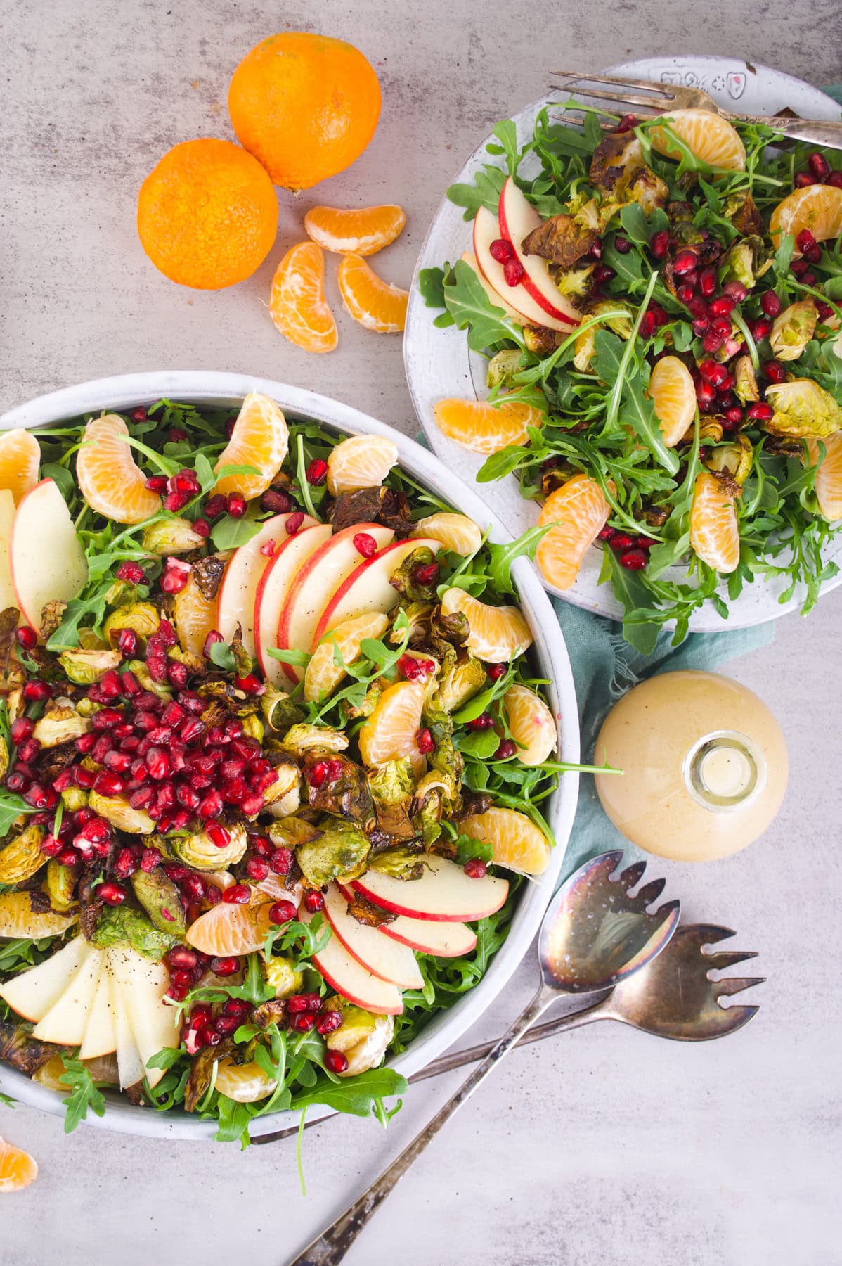 Fresh fruit and arugula salad with pomegranate seeds, apple slices, mandarin oranges, and roasted Brussels sprouts.
