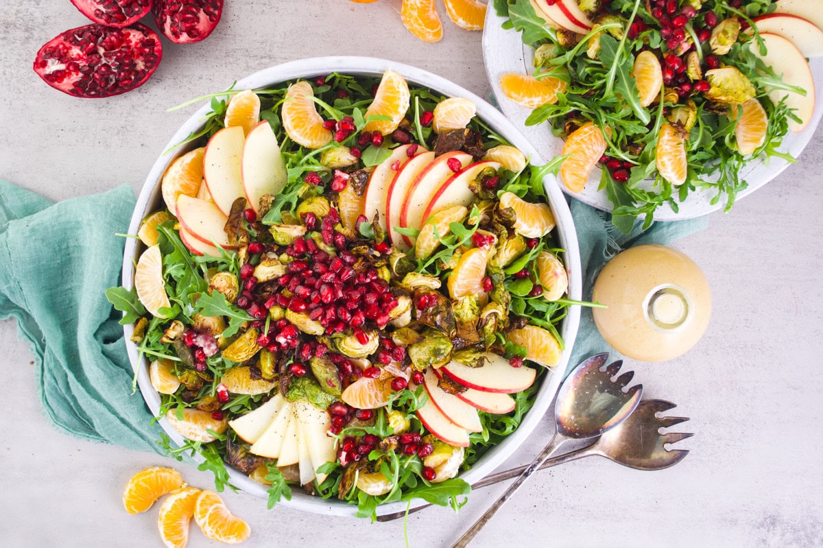 Fresh autumn salad with apples, oranges, pomegranate seeds, roasted Brussels sprouts, and arugula. Perfect for healthy, holistic meals.