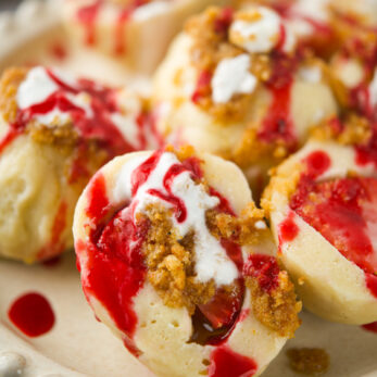 Polish Strawberry Knedle ( Potato Dumplings Gluten-Free) with bread crumbs and drizzled with white cream. The dessert looks creamy and inviting.