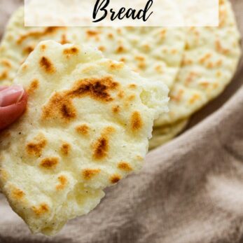 A hand holds a piece of gluten-free naan bread over a plate with more naan on a beige cloth. Text at the top reads, Gluten-Free Naan Bread. Website thetastesoflife.com appears at the bottom.