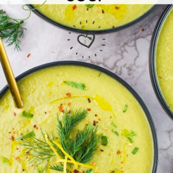 Top view of bowls filled with creamy leek fennel soup, garnished with fresh dill, lemon zest, and chives. A gold spoon rests in one bowl. Text overlay reads, Creamy Leek Fennel Soup.