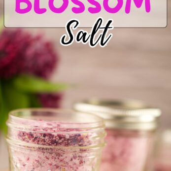 A small glass jar filled with pinkish-purple lilac blossom salt sits on a beige surface, with another jar and lilac flowers blurred in the background. Text reads Easy Lilac Blossom Salt and get the recipe.