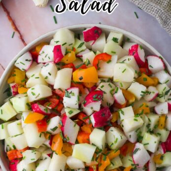 A bowl of colorful chopped kohlrabi salad with diced radishes, peppers, and herbs sits on a table next to a spoon, with text promoting a homemade kohlrabi salad recipe.