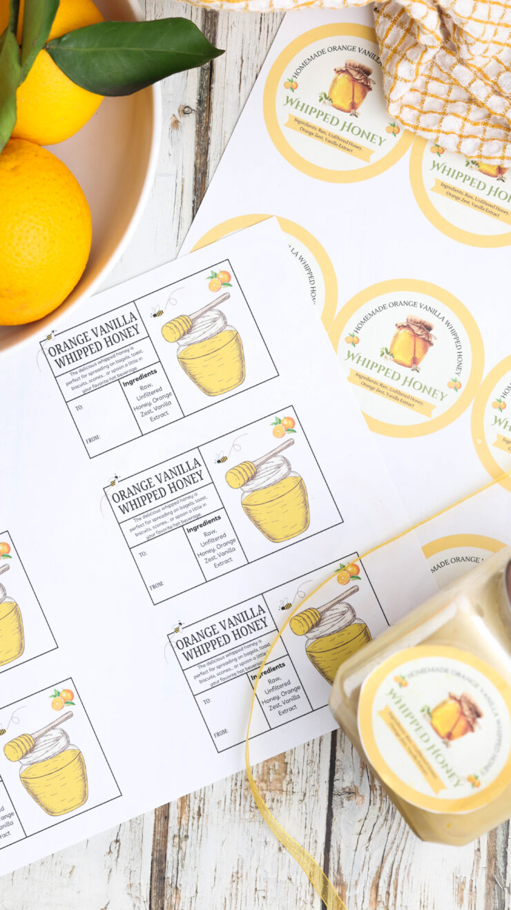 A sheet of printable labels for Orange Vanilla Whipped Honey jars, displayed next to fresh oranges and a glass jar of the honey.