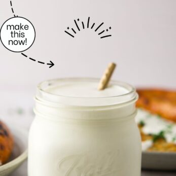 A glass jar filled with Polish Homemade Horseradish Condiment (Chrzan), with a wooden spoon inside, sits on a light surface. Green herbs and food are blurred in the background. Text above reads: Polish Homemade Horseradish Condiment (Chrzan) Gluten-Free.