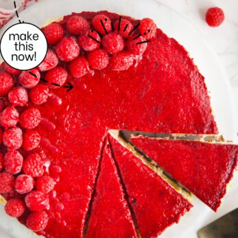 Polish raspberry cheesecake topped with fresh raspberries and glossy raspberry glaze sits on a white surface. One slice is cut and being served. Red and white text labels describe it as Polish Raspberry Cheesecake.