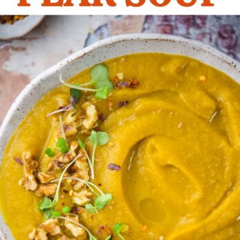 A bowl of creamy roasted sweet potato pear soup, topped with chopped walnuts, microgreens, and spices.