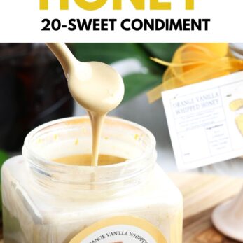 A spoon drizzles creamy orange vanilla whipped honey from a clear jar with a product label, next to orange slices and a recipe tag.