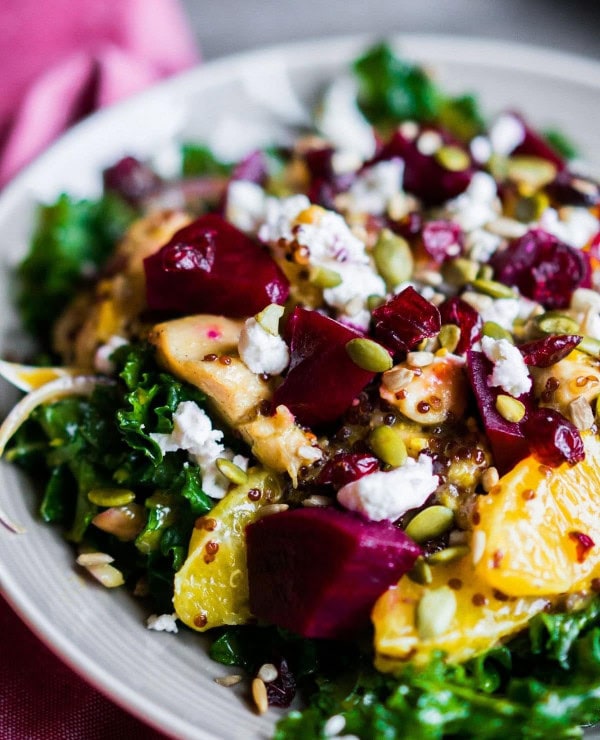 A colorful salad A Roundup Image for Delicious Dinner Recipes kale, orange slices, roasted beets, quinoa, crumbled feta cheese, and sprinkled pumpkin seeds, served on a white plate.